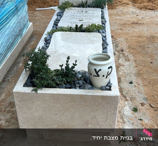 מצבה עם כיתוב בעברית ועיטור לבבות